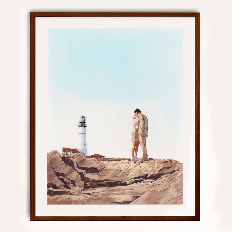 May include: A framed watercolour print shows a couple embracing on a rocky cliff with a lighthouse in the background. The lighthouse is white with a black top, and the sky is pale blue. The rocks are brown and tan.