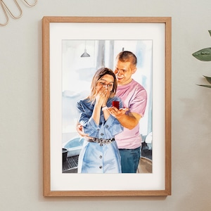 May include: Watercolor painting in a wooden frame depicts a proposal scene. A woman in a blue dress covers her mouth, reacting to a man holding a ring box. The man wears a pink shirt, smiling. The artwork is set against a window background.