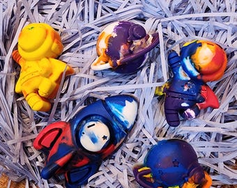 May include: A set of five colorful space-themed bath toys made of silicone. The toys include an astronaut, a rocket, a planet, and two stars. The toys are all different colors and have a variety of textures.