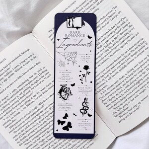 May include: A dark blue bookmark with the text "Dark Romance Ingredients" and black and white illustrations of a spider web, a black rose, a heart, a dagger, a snake, and butterflies.