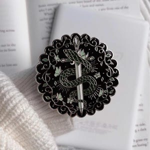 May include: A white ceramic mug with a black handle and the text "But First, Coffee" in a black, handwritten-style font. The mug is on a white surface.