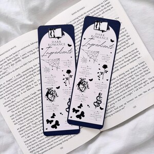 May include: Two black and white bookmark designs with the text "Dark Romance Ingredients" and illustrations of black roses, hearts, daggers, butterflies, and a spider web.