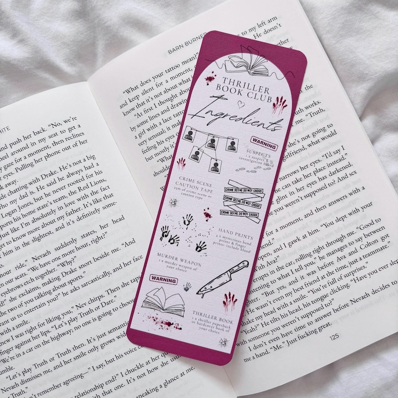 May include: A pink bookmark with a red heart and the text "Thriller Book Club Ingredients" in white. The bookmark features illustrations of crime scene tape, hand prints, a murder weapon, a book, and a warning sign. The bookmark is designed to look like a crime scene.