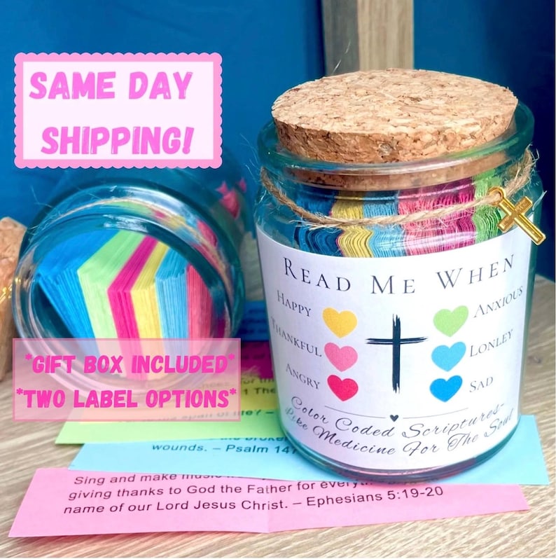 May include: A glass jar with a cork lid, filled with colorful paper strips. The jar has a label that reads "Read Me When" with various emotions listed. A gold cross charm hangs from the jar. The text "Color Coded Scriptures - Like Medicine For The Soul" is also visible.