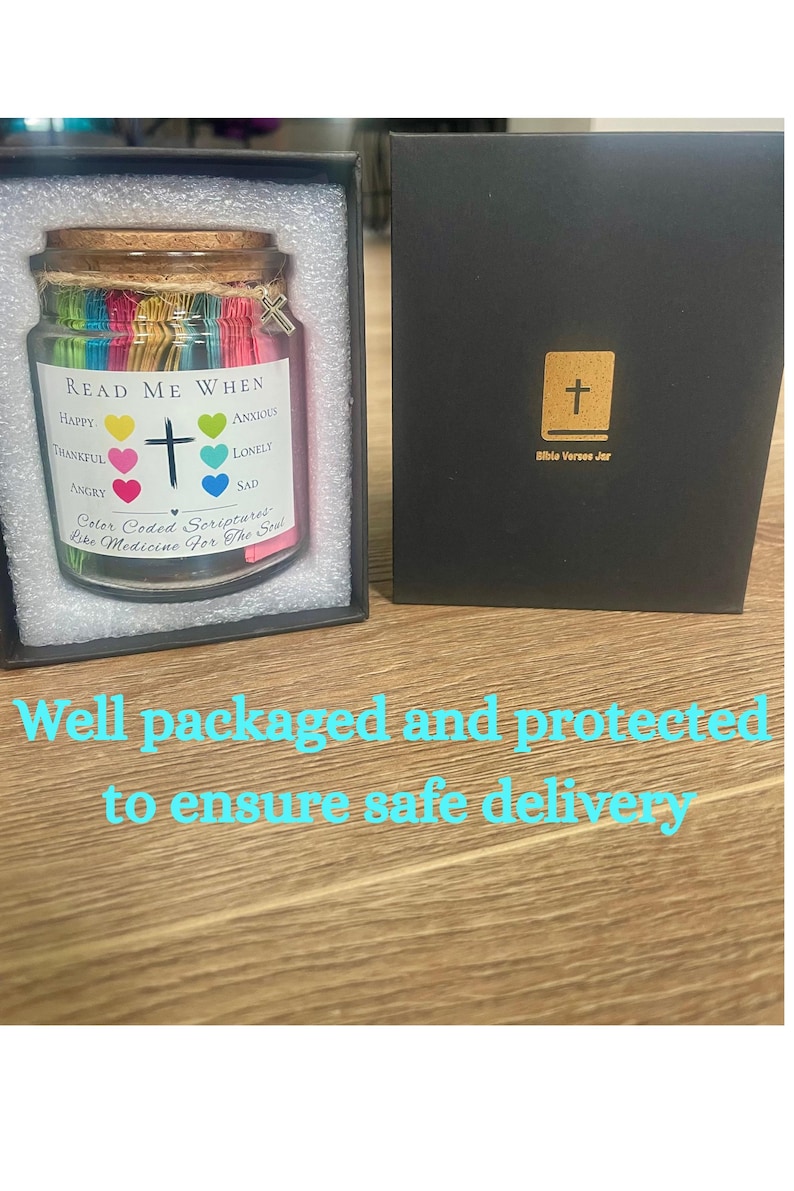 May include: A glass jar filled with colorful paper strips, labeled "Read Me When" with emotions like happy and sad. A cross charm hangs from the lid. The jar is in a black box with a gold cross.