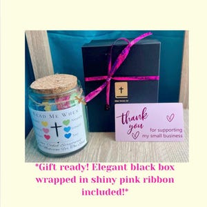 May include: A glass jar with a cork lid, filled with colorful paper hearts and the text "Read Me When." A black box with a pink ribbon and a card that says "Thank you for supporting my small business" are also in the image.