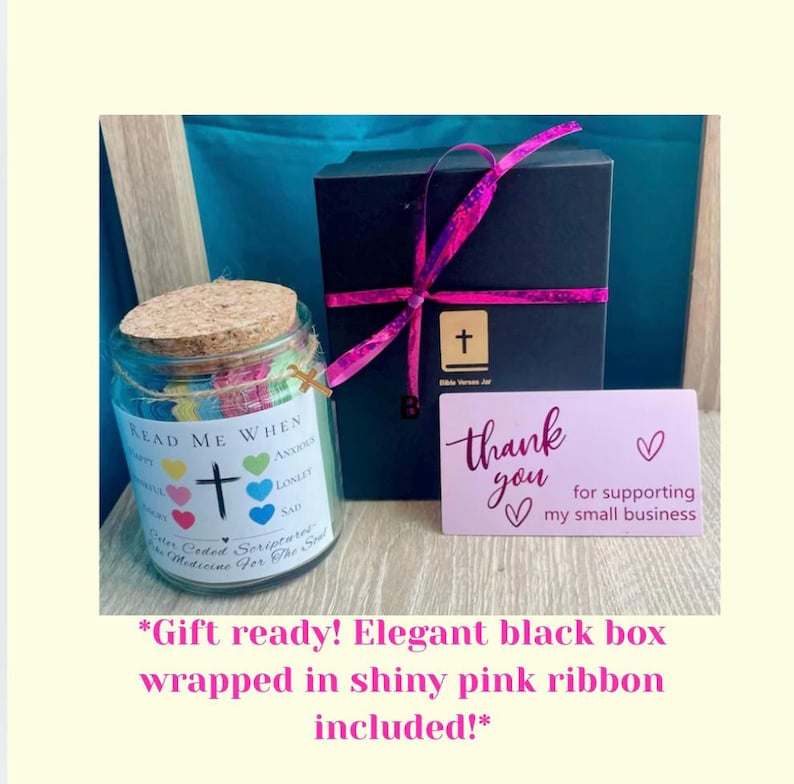 May include: A glass jar with a cork lid, filled with colorful paper hearts and the text "Read Me When." A black box with a pink ribbon and a card that says "Thank you for supporting my small business" are also in the image.