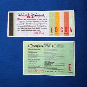 May include: Two rectangular Disneyland ticket stubs. The top ticket features a welcome message, the Disneyland logo, and vertical color-coded sections labeled A through E. The bottom ticket is a green E-coupon listing various attractions.