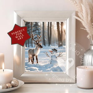 May include: A framed winter scene featuring a reindeer and snowman in a snowy forest. The image is in a silver frame, with a red star-shaped sticker that says "PERFECT FOR WALL ART". The scene is flanked by lit candles and a decorative vase.