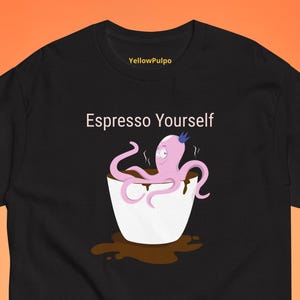 以下が含まれることがあります： 白いコーヒーカップと青い王冠をかぶったピンクのタコが描かれた黒いTシャツ。Tシャツには「Espresso Yourself」という文字が印刷されています。