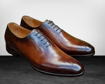 Puede incluir: Un par de zapatos de vestir de cuero marrón con cordones y acabado pulido.