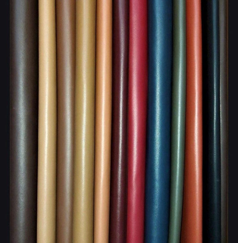 K&ouml;nnte beinhalten: Vertikale Darstellung verschiedenfarbiger Lederst&uuml;cke. Die Farben reichen von Dunkelbraun bis Hellbeige, mit Schattierungen von Rot, Blau und Gr&uuml;n. Das Leder wirkt glatt und hat einen leichten Glanz.