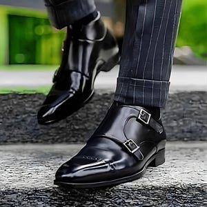 May include: Black leather monk strap shoes with two buckles on each shoe. The shoes have a pointed toe and a polished finish.