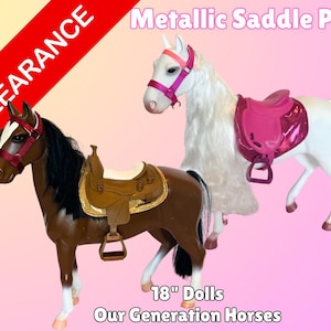 Puede incluir: Dos caballos de juguete para muñecas de 46 cm. Un caballo es marrón con una silla de montar marrón y una brida roja. El otro caballo es blanco con una silla de montar rosa y una brida rosa. El texto "Metallic Saddle Pad" y "18" Dolls Our Generation Horses" es visible en la imagen.