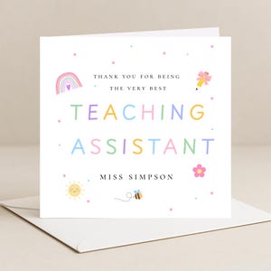 May include: A square white greeting card featuring the text THANK YOU FOR BEING THE VERY BEST TEACHING ASSISTANT MISS SIMPSON in colourful letters. The design includes illustrations of a rainbow, a pencil with a bow, a sun, a bee, and a flower.