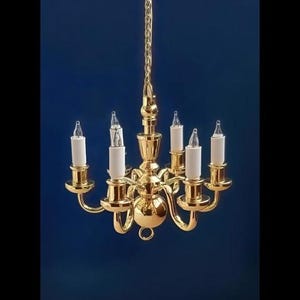 May include: A gold-colored chandelier with six candle-shaped lights. The fixture is suspended from a gold chain against a dark blue background. The text "FA018004" is at the bottom.