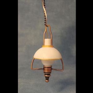 Op de afbeelding: Een miniatuur hanglamp met een witte koepelvormige kap met een dunne gele rand, opgehangen aan een koperkleurige ketting. Het armatuur bevat een koperkleurig metalen frame en een centraal onderdeel dat op een gloeilamp lijkt.