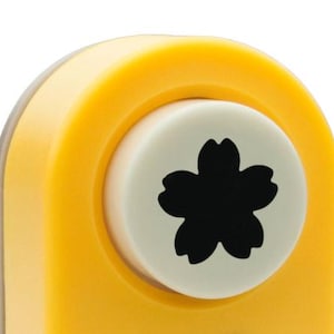 Op de afbeelding: Gele papierpons met een witte ronde matrijzen met een zwarte vijfbladige bloem.