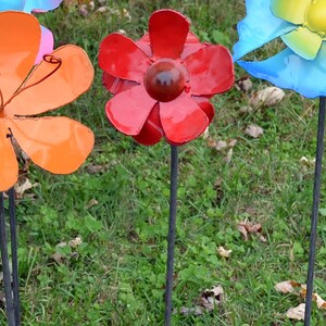 Puede incluir: Un conjunto de flores de metal de colores con tallos largos. Las flores est&aacute;n hechas de metal y tienen un acabado brillante. Las flores son rojas, naranjas, azules y amarillas.