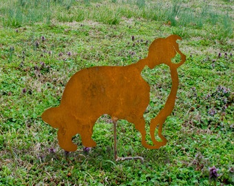 May include: A rusty metal silhouette of a dog standing in a grassy field. The dog is facing to the left and has its head tilted down.