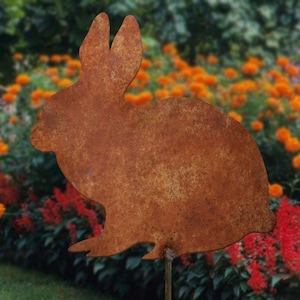 May include: A rusty metal rabbit silhouette garden stake. The stake is brown and orange with a weathered look. The rabbit is facing the right side of the image.