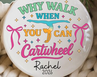May include: A round white ceramic ornament featuring a colourful graphic of a gymnast performing a cartwheel. The text reads Why Walk When You Can Cartwheel, with the name Rachel and the year 2026 printed below in black script and font.