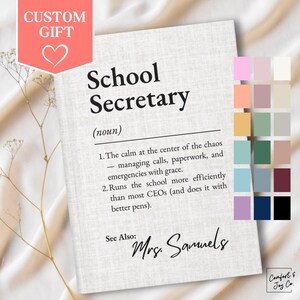May include: A personalized notebook with the text "School Secretary" and a definition. The notebook has a light beige textured cover with a custom gift label and a heart icon. The name "Mrs. Samuels" is written below the definition.