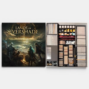 May include: A board game box titled Lands of Evershade with fantasy artwork on the lid. The open box reveals a black plastic insert containing organized compartments filled with stacks of cards, small tokens, dice, and miniature game pieces.
