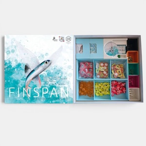 Könnte beinhalten: Eine Brettspielschachtel mit dem Titel Finspan und einer Illustration eines fliegenden Fisches auf dem Deckel, sowie ein offenes Schachtelinnere mit organisierten Fächern, die mit verschiedenen kleinen Kunststoffmarkern in Rot, Orange, Gelb und Weiß gefüllt sind.