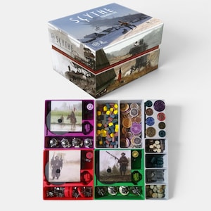 May include: A Scythe Legendary Box board game set featuring a large illustrated storage box and four colorful plastic organizer trays. The trays contain various game components including small wooden cubes, circular tokens, and miniature figures.
