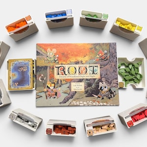 Puede incluir: El juego de mesa "Root" se muestra con varias piezas de juego en contenedores individuales. La caja del juego presenta ilustraciones coloridas de criaturas del bosque. Las piezas del juego son de varios colores, incluyendo naranja, azul, verde, amarillo, rojo y morado.
