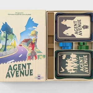 Puede incluir: Una caja de juego de mesa titulada Agent Avenue con una ilustración de un zorro en una calle suburbana. La caja abierta contiene dos mazos de cartas en soportes azul oscuro y verde, junto con piezas de juego de madera azul y verde.