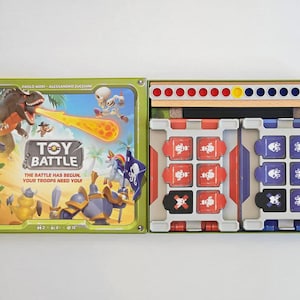 以下が含まれることがあります： 恐竜や騎士のカラフルなイラストが描かれたボードゲーム「Toy Battle」。ゲームボックスは開いており、ゲームの駒と色付きのペグが付いた木製のボードが表示されています。