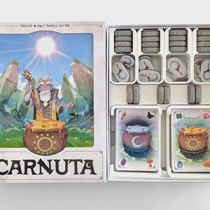 Può includere: Scatola di gioco da tavolo aperta, che rivela pezzi e carte. L'illustrazione della scatola presenta un mago con un bastone e un calderone. Il titolo del gioco "CARNUTA" è visualizzato in basso. Il set include gettoni e carte.