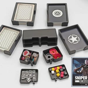 May include: A black plastic board game organizer set for Sniper Elite, including card trays, token bins, and a central storage unit. The set features various game components like decks of cards, red, yellow, and black cubes, and circular tokens.