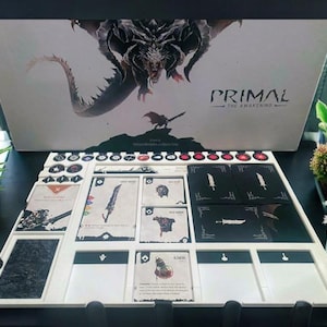 Può includere: Un tabellone da gioco bianco con slot per carte bianche e nere e un vassoio per pezzi da gioco bianchi e neri. Il tabellone è etichettato "Primal: The Awakening".
