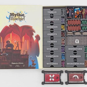 May include: Open board game box titled "Mythic Mischief." The box art features a fantasy scene with figures and the text "Highstakes Hijinks." Inside, gray storage containers are labeled with fantasy creature names like "Trolls" and "Gargoyles," holding game pieces.