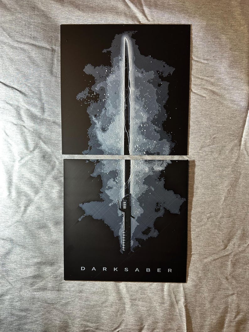 K&ouml;nnte beinhalten: Zwei schwarze rechteckige Kunstdrucke mit einer stilisierten Illustration des Darksaber. Das Kunstwerk zeigt das Lichtschwert mit wei&szlig;en und grauen Akzenten vor einem dunklen Hintergrund. Das Wort "DARKSABER" ist unten aufgedruckt.
