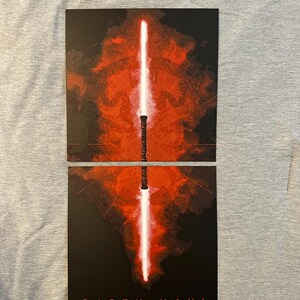K&ouml;nnte beinhalten: Zweiteiliger Kunstdruck mit einem rot-wei&szlig;en Lichtschwert-Design vor dunklem Hintergrund. Die Worte "DARTH MAUL" sind unten auf dem Druck in Wei&szlig; gedruckt. Das Lichtschwert ist zwischen den beiden Teilen geteilt.