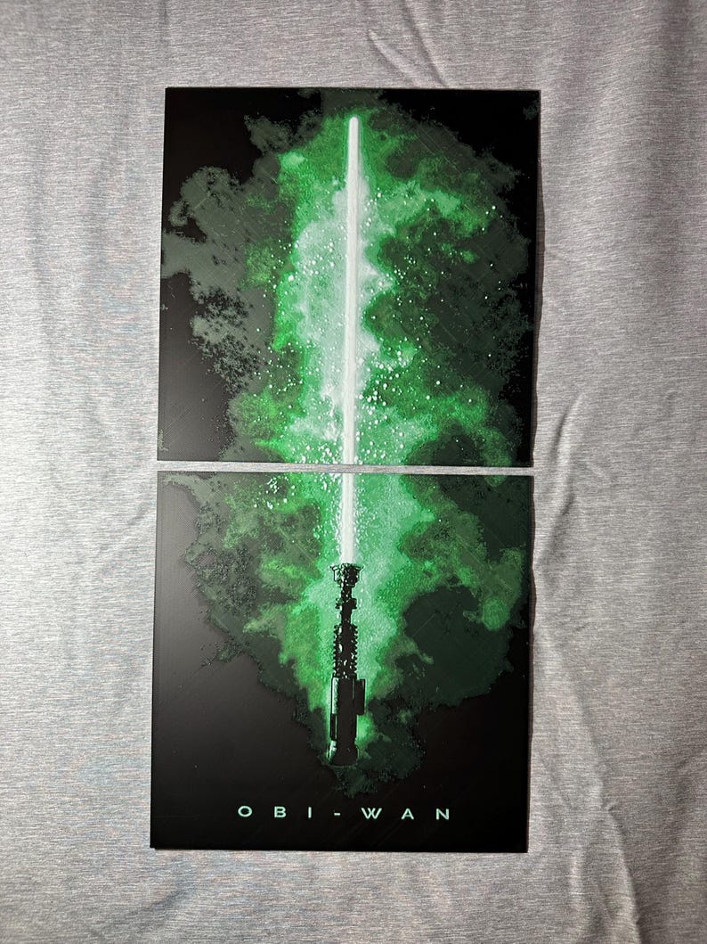 K&ouml;nnte beinhalten: Zweiteiliges Kunstwerk mit einem gr&uuml;nen Lichtschwert vor dunklem Hintergrund mit einem gr&uuml;nen und wei&szlig;en Nebel-Effekt. Das Wort "OBI-WAN" ist unten in Wei&szlig; aufgedruckt.