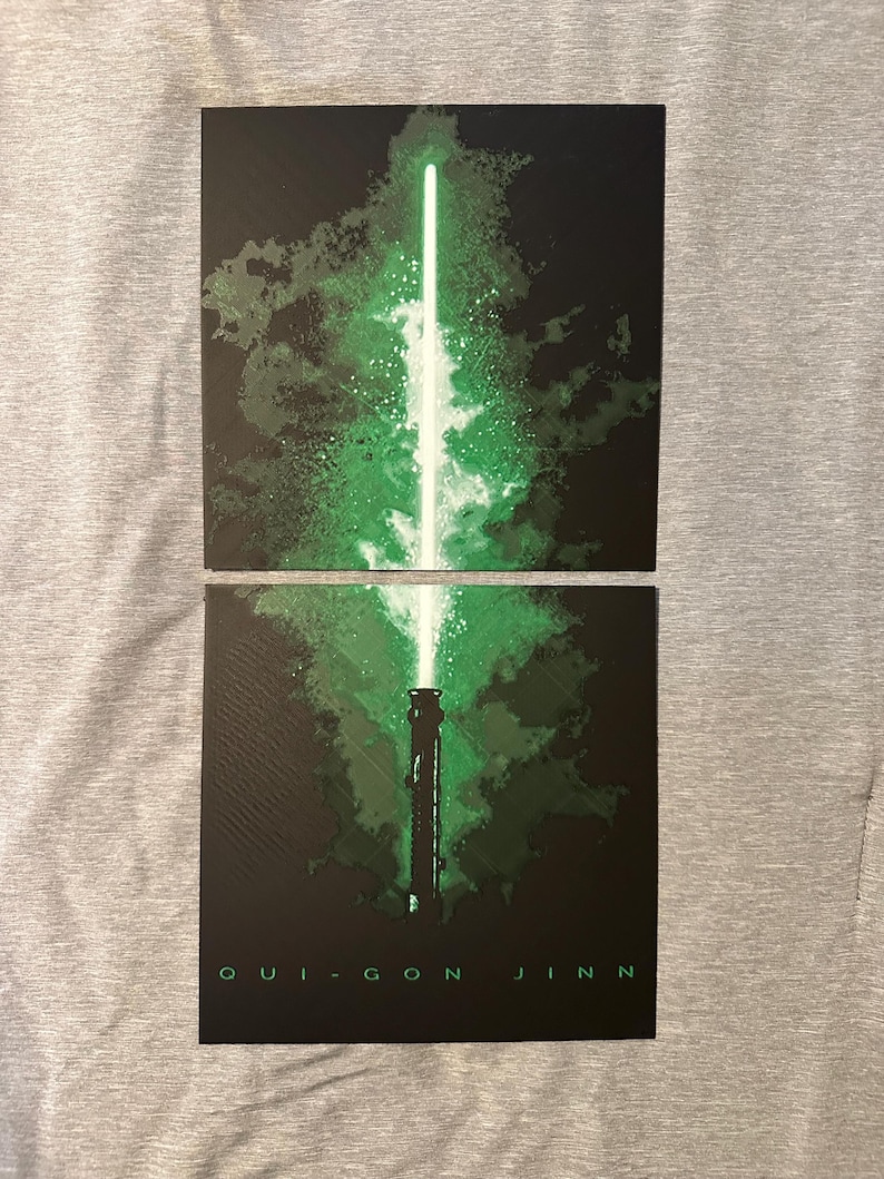 K&ouml;nnte beinhalten: Zweiteilige Grafik mit einem gr&uuml;nen Lichtschwert-Design vor schwarzem Hintergrund. Das Lichtschwert hat eine leuchtend gr&uuml;ne Klinge und einen detaillierten Griff. Der Text "QUI-GON JINN" ist unten in Wei&szlig; gedruckt.