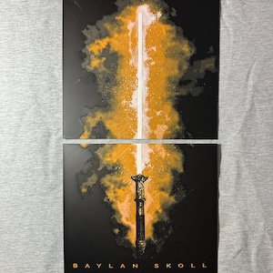 K&ouml;nnte beinhalten: Zwei schwarze, rechteckige Kunstdrucke mit einer stilisierten Illustration eines leuchtenden wei&szlig;en und orangefarbenen Lichtschwerts. Das Lichtschwert ist vor einem dunklen Hintergrund platziert, mit dem Text "BAYLAN SKOLL" am unteren Rand des unteren Drucks.
