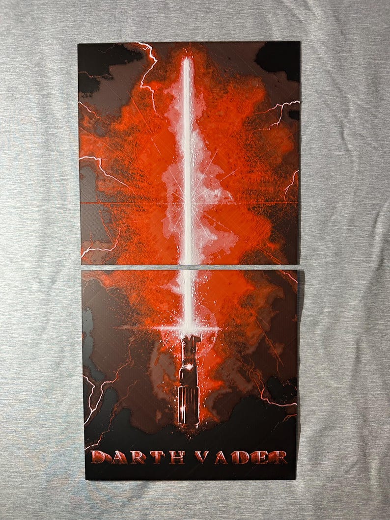 K&ouml;nnte beinhalten: Zweiteiliges Kunstwerk mit rotem und schwarzem Hintergrund und einem wei&szlig;en Lichtschwert. Der untere Teil zeigt den Text "Darth Vader" in Rot. Blitzartige Streifen sind im gesamten Kunstwerk sichtbar.