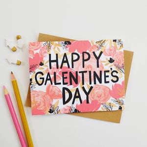 May include: A pink and white card with a floral pattern and the text "Happy Galentine's Day" in black.