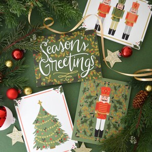 May include: Four Christmas cards with different designs. One card features a green tree with gold ornaments, another has a red and gold nutcracker, and another has three nutcrackers in a row. The last card has a green background with the text "Season's Greetings" in white.