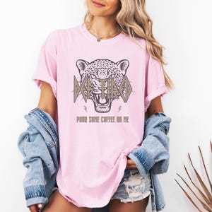 May include: A pink t-shirt featuring a graphic of a jaguar's head with the text "I'm Tired" and "Pour some coffee on me".