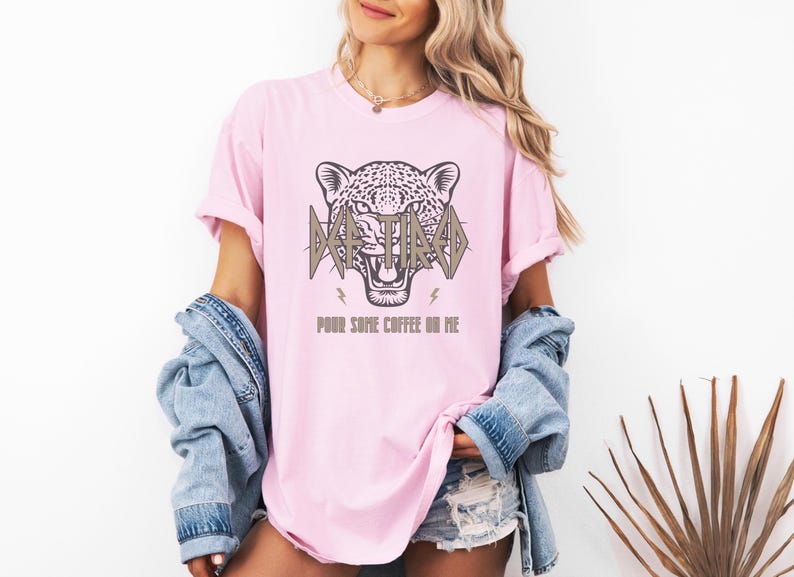 May include: A pink t-shirt featuring a graphic of a jaguar's head with the text "I'm Tired" and "Pour some coffee on me".