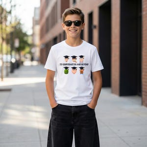 A young boy wearing a white t-shirt with a graphic design and smiling at the camera.