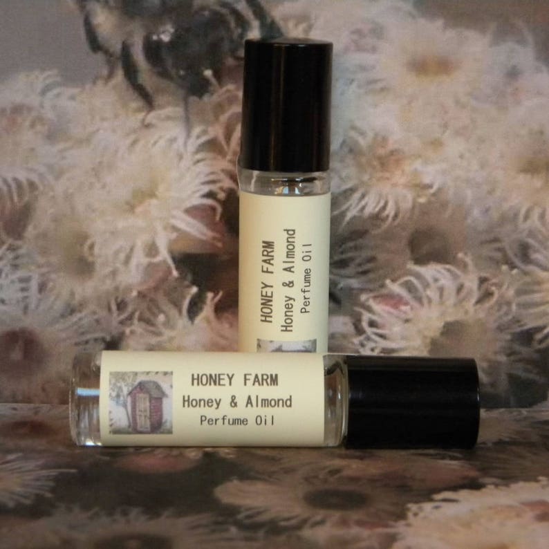 May include: Two small glass bottles of Honey Farm Honey & Almond Perfume Oil. The bottles have a white label with black text and a small illustration of a house.