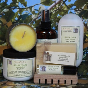 May include: A set of bath and body products in a lemon verbena scent. The set includes a candle, body butter, shea butter soap, hand whipped soap, and perfume oil. All products are labeled "Mellow Yellow" and "Country Folk Soap".
